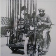 A police officer on a Harley and an old fashioned mobile holding cell. (1921)
